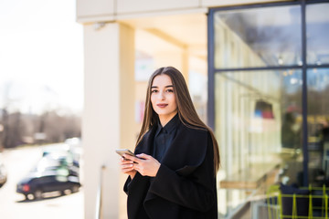 Business woman speaking cellphone on the street in front of office building