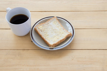 Black coffee and bread on wooden of brown