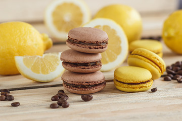 Yellow and brown french macarons with lemons and coffee beans on the wooden board