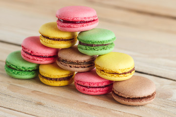 Green, pink, yellow and brown french macarons on the wooden boards