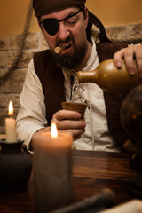 Pirat schenkt sich weißen Rum ein, Konzept Mottoparty und Mittelalter