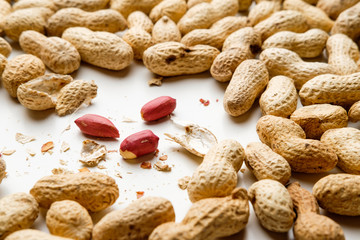 Cracked peanuts and peanuts in nutshell on white background