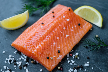 Raw salmon lemon salt and pepper on the background of the black stone