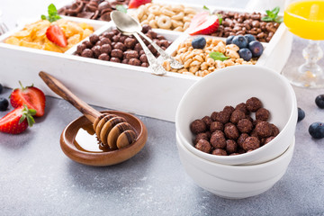 Variety of cold quick breakfast cereals with berries in white wooden box, healthy eating for kids, selective focus.