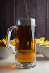 Lager beer in glass and potato chips on wooden background