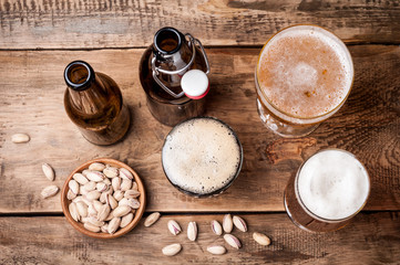 Beer in bottles and glasses on a wooden table. Beer and snacks pistachio nuts top view. Drink and snack for the football match or rest in pub