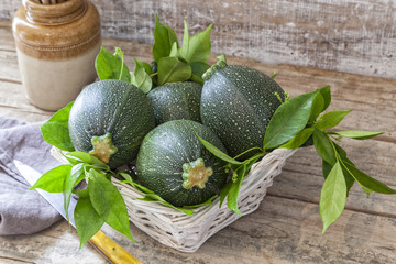 Round zucchini in a basket on a wooden table