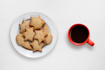 Coffee cup and cookies in plate on white wooden table