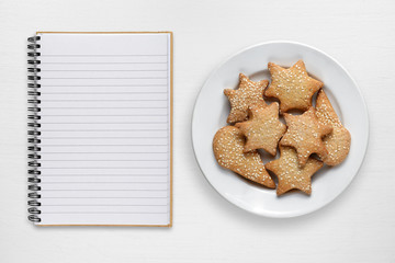 Blank recipe book and cookies on white table
