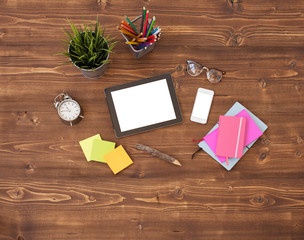 Tablet computer and office supplies on wooden background