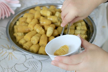 Preserved banana with syrup in stainless tray. Thai style, served on a white plate with a hand holding.