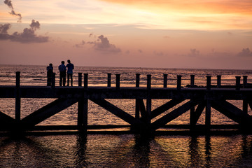 Obraz premium siluate picture 3 man walking on the bridge when sunset time