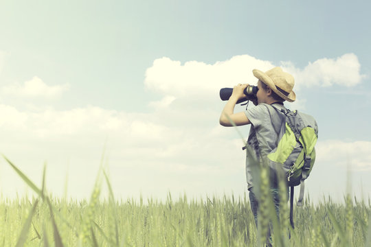 Young child explorer looks at the infinite with his binoculars