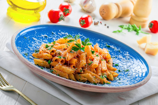 Traditional Italian penne pasta with arrabiata tomato sauce on a blue rustic plate. Delicious healthy Mediterranean cuisine food.