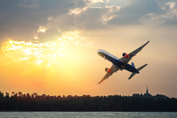 Fototapeta na wymiar Airplane flying through the sea at sunset
