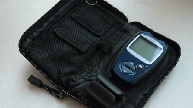 Close-up shot of woman hand taking from the case container with blood test strips, lancing device and glucometer