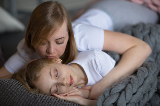 Blond mom and daughter teenager sleep hug on bed