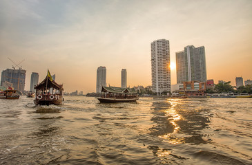 BANGKOK, THAILAND, MARCH 02, 2017 - Chao Praya River in Bangkok, buildings and boats at sunset