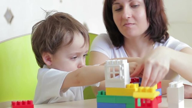 Mother and her child are playing with colored blocks