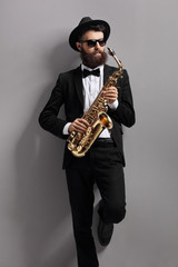Saxophone player leaning against a wall