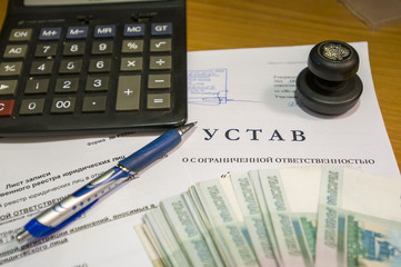 На столе в кабинете лежит устав предприятия,  ручка,...