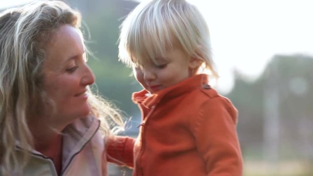 Smiling blond child kiss mum outdoor in winter time