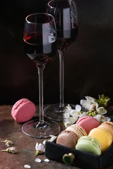 Gardinen Two glasses of port wine with variety of colorful french sweet dessert macaron macaroons with different fillings served with spring flowers over dark texture background. Celebration concept © Natasha Breen