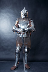 A medieval warrior in a helmet and with a sword. Knight on dark background