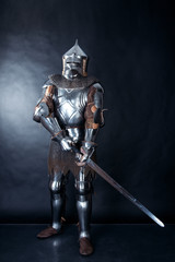 A medieval warrior in a helmet and with a sword. Knight on dark background