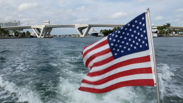 American flag waves on a boat navigating in a canal in Fort Lauderdale, Florida.
