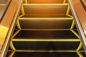 Electric escalator in yellow bands and metal line steel