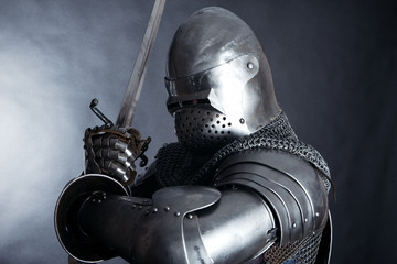 A medieval warrior in a helmet and with a sword. Knight on dark background