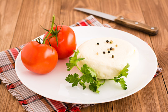 Сыр, помидор и петрушка на тарелке на деревянном столе