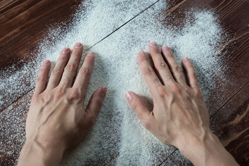 female hands on the wooden table sprinkled with flour