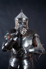 Fototapeta premium A medieval warrior in a helmet and with a sword. Knight on dark background