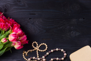 female flat lay scene border - fresh tulips flowers and accessories on black wooden background