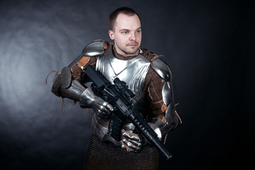 A medieval warrior with firearms. Knight with assault rifle on dark background