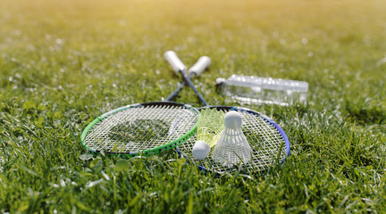 Two badminton rackets and a bottle of water shot at sunset - 147520501