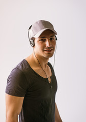 A young man with headphone listening to music looking at camera and smiling, on white background