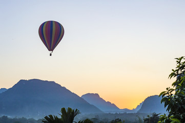 Hot air balloon flying over the mountains in the sunset time in Vang Vieng, Laos