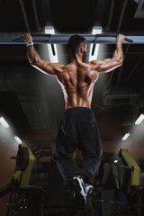 Back view of muscular man doing pull up exercise