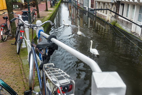 Canal with tunnel and historic street with bicycle parking lot in Dutch Delft old city