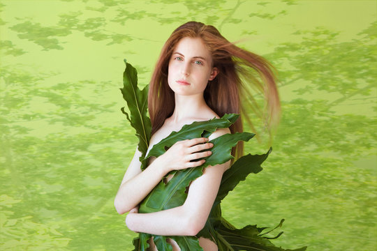 Young woman wrapped in large leaf