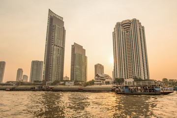 BANGKOK, THAILAND, MARCH 02, 2017 - Chao Praya River in Bangkok, buildings and boats at sunset