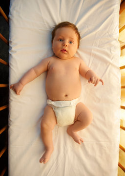Baby in nappy/diaper lying in cot