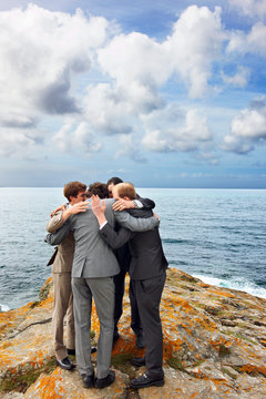 Businessmen talking in huddle on cliff