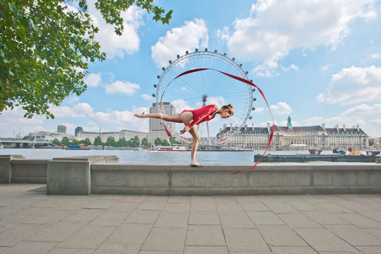 Gymnast twirling ribbon on city street