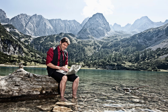 Man using laptop by lake