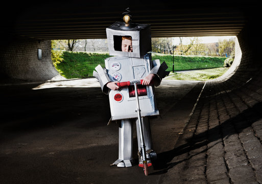 Boy dressed as robot riding scooter