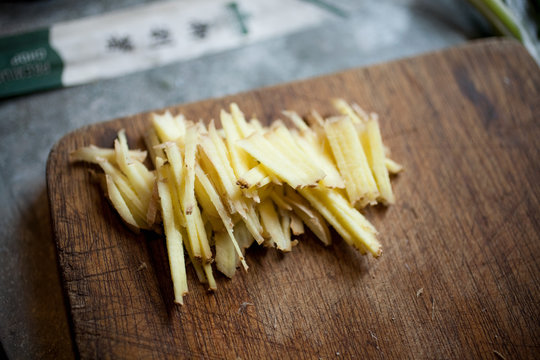 Sliced fresh root ginger on wooden chopping board